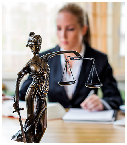 Juristin am Schreibtisch auf dem eine Figur von Justizia steht